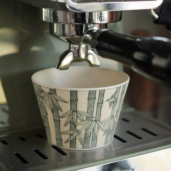 Vintage bamboo forest ceramic coffee mug placed under a coffee machine, filled with freshly brewed coffee.