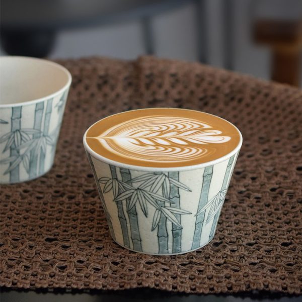 Vintage blue and white coffee mug filled with latte art, placed on a coffee-colored crochet tablecloth.