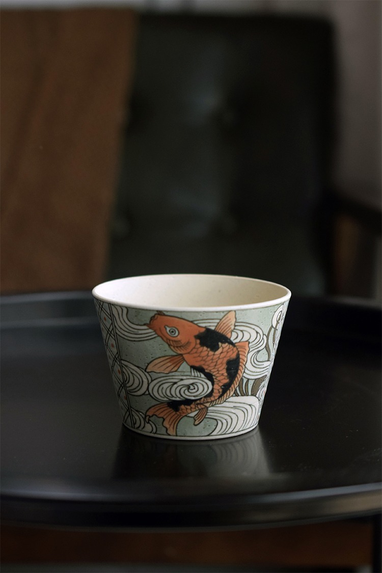 Blue and white porcelain tea cup features hand-painted koi, enhancing the tea experience with traditional Chinese elegance.