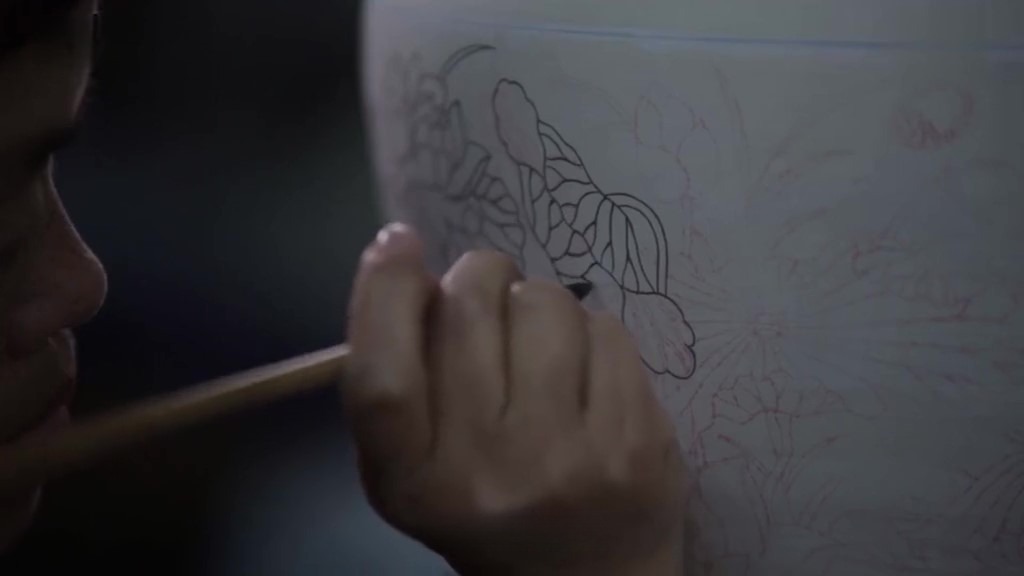The process of drawing the basic lines or contours of a design, often with ink or a fine tool, to define the structure of the artwork