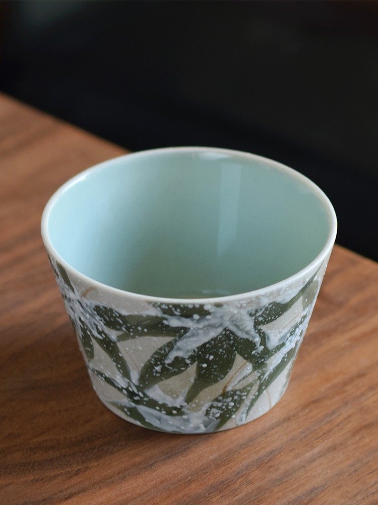 Interior detail of hand-painted snowy bamboo ceramic cup with smooth celadon glaze and refined finish