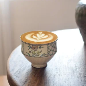 Display a customized handmade ceramic coffee cup on a wooden desk, ideal for artistic middle-class lifestyles