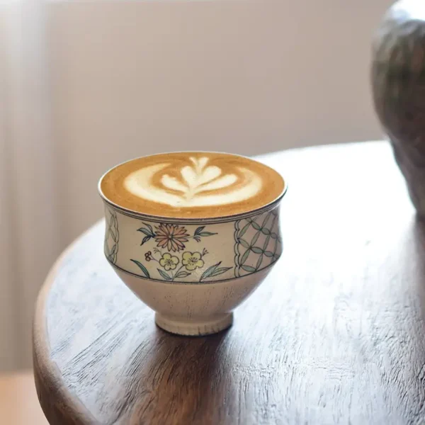 Display a customized handmade ceramic coffee cup on a wooden desk, ideal for artistic middle-class lifestyles