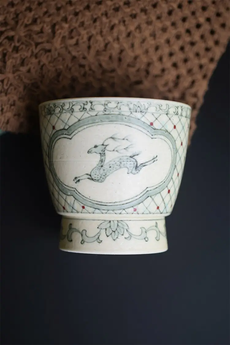 Custom ceramic cup features hand-painted blue deer motif to express refined Eastern artistry