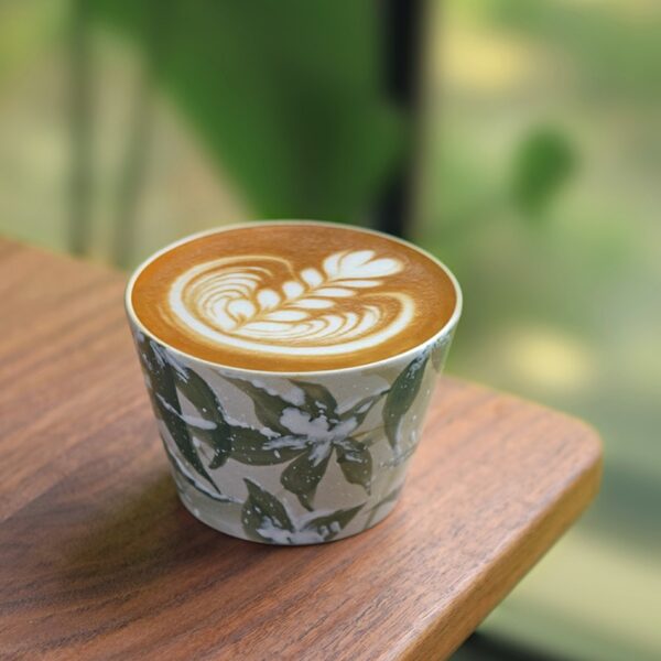 Green bamboo pattern ceramic cup filled with coffee, placed at table corner with elegant