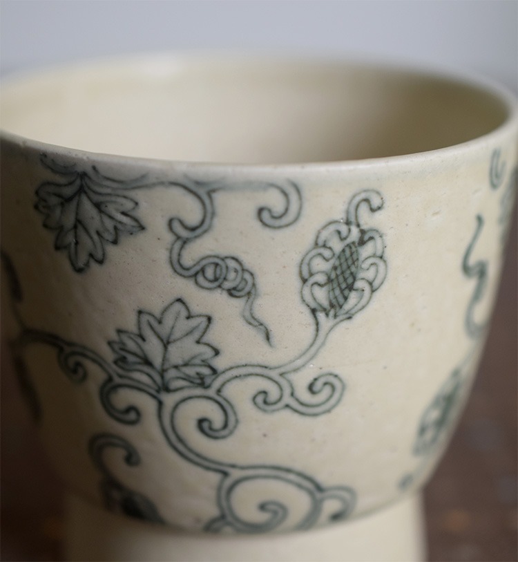Detail of handcrafted ceramic coffee cup with hand-painted blue lychee pattern, showing artisan quality.