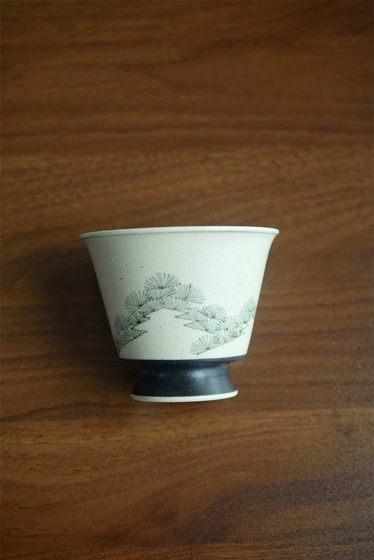 Close-up of handmade ceramic coffee cup with pine tree painting, vintage Chinese style.