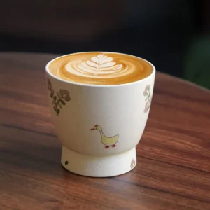 Handmade coffee mug with hand-painted goose design, perfect for latte art lovers.