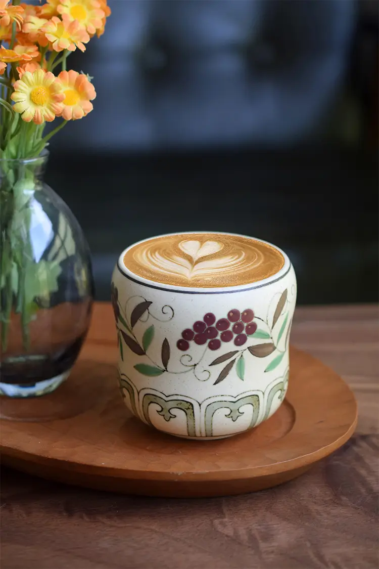 Handmade coffee mug showcases grape Chanzhi pattern, adding timeless charm to a teacher's desk.