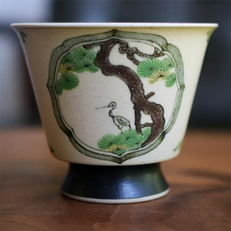 Handmade porcelain tea cup with hand-painted pine and crane detail, symbolizing longevity—ideal gift for elders.