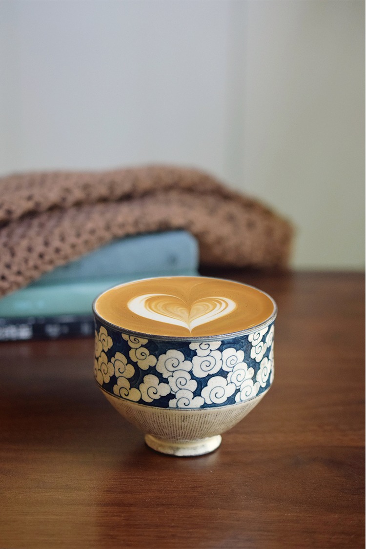 Hand-painted underglaze cloud ceramic cup filled with latte featuring heart-shaped art, handcrafted finish