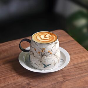 Handcrafted ceramic cup and saucer filled with coffee, hand-painted lily flower design, perfect for summer