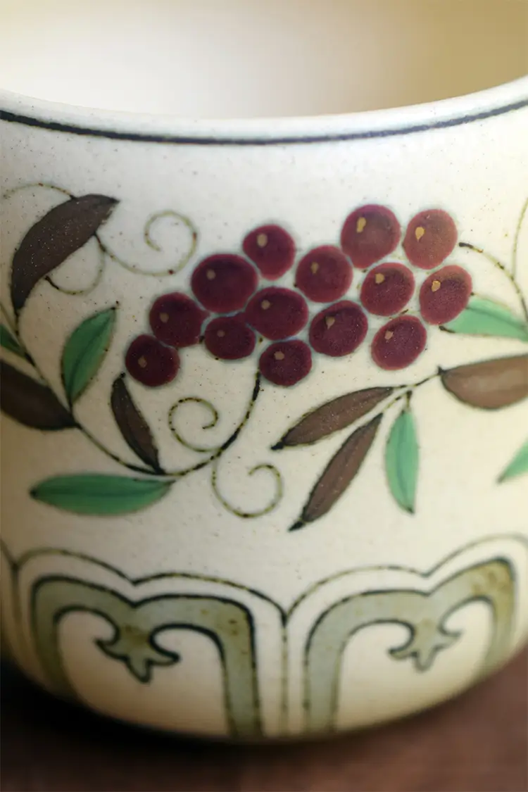 Vintage coffee cup showcases hand-painted grape tendril design with exquisite craftsmanship.
