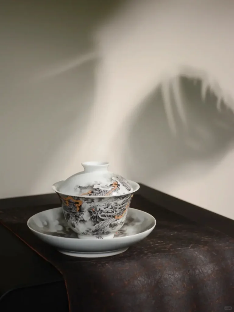 Close-up of matching tea cup and saucer set featuring intricate blue-and-white brushwork by Xiaogu Tang studio artists