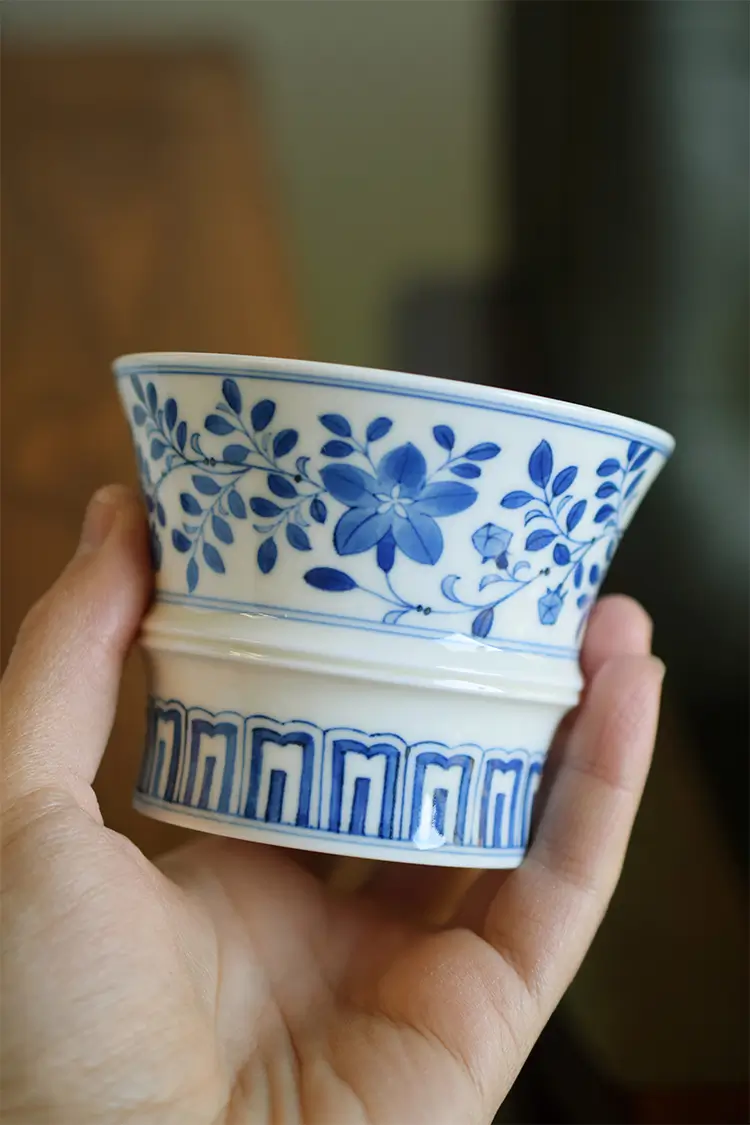 Handmade blue and white ceramic coffee cup showcases underglaze brushwork with traditional Chinese floral motifs.
