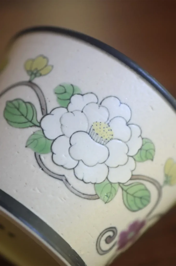 Handmade ceramic coffee cup showcases hand-painted white camellia pattern with elegant brushwork.