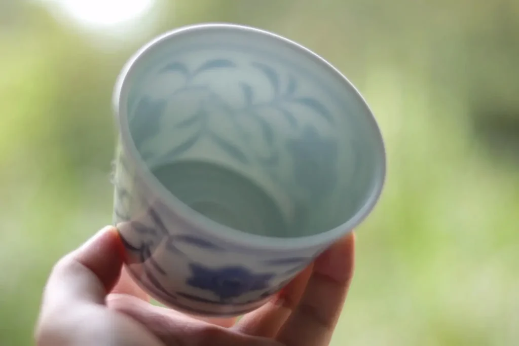 Handmade thin-body ceramic coffee mug with elegant blue and white vine pattern.