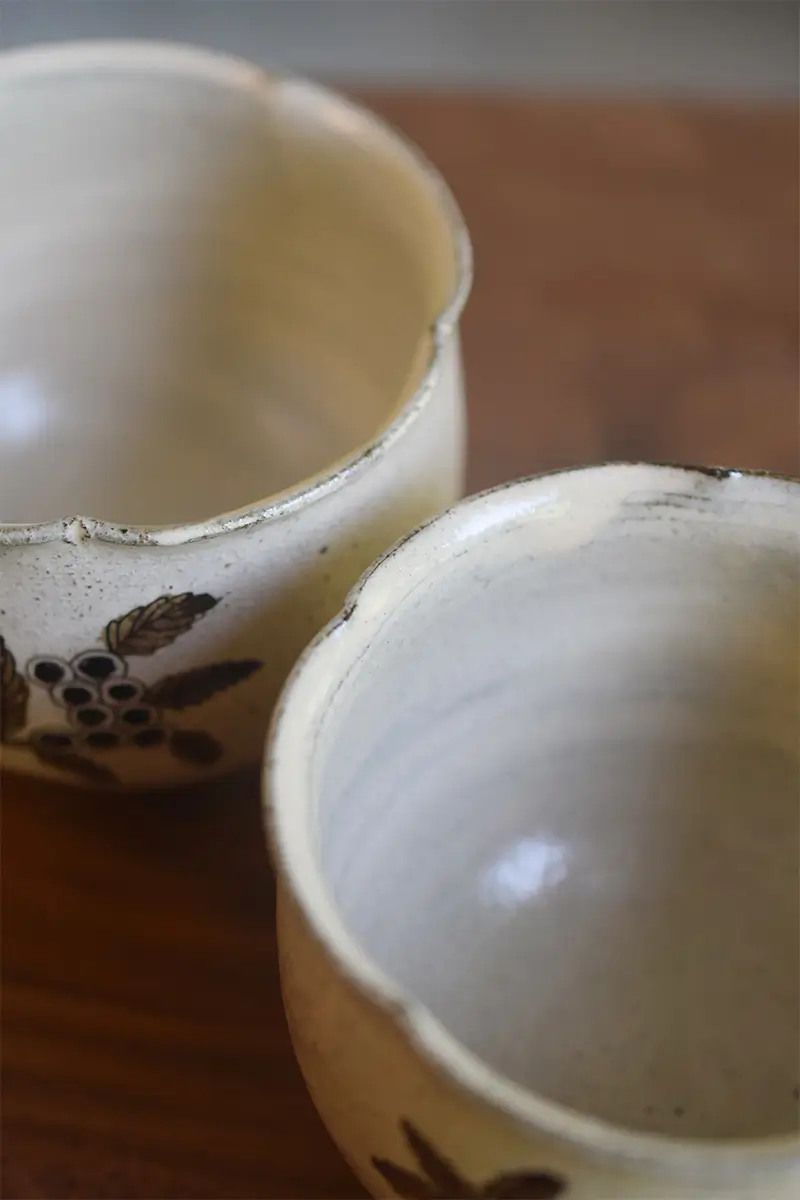 Handmade ceramic cup with flower-rim design and clean, smooth glaze, showcasing elegant craftsmanship.