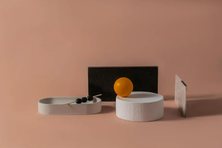 Modern abstract composition featuring ceramic shapes and textures on a pink background with a minimalist aesthetic