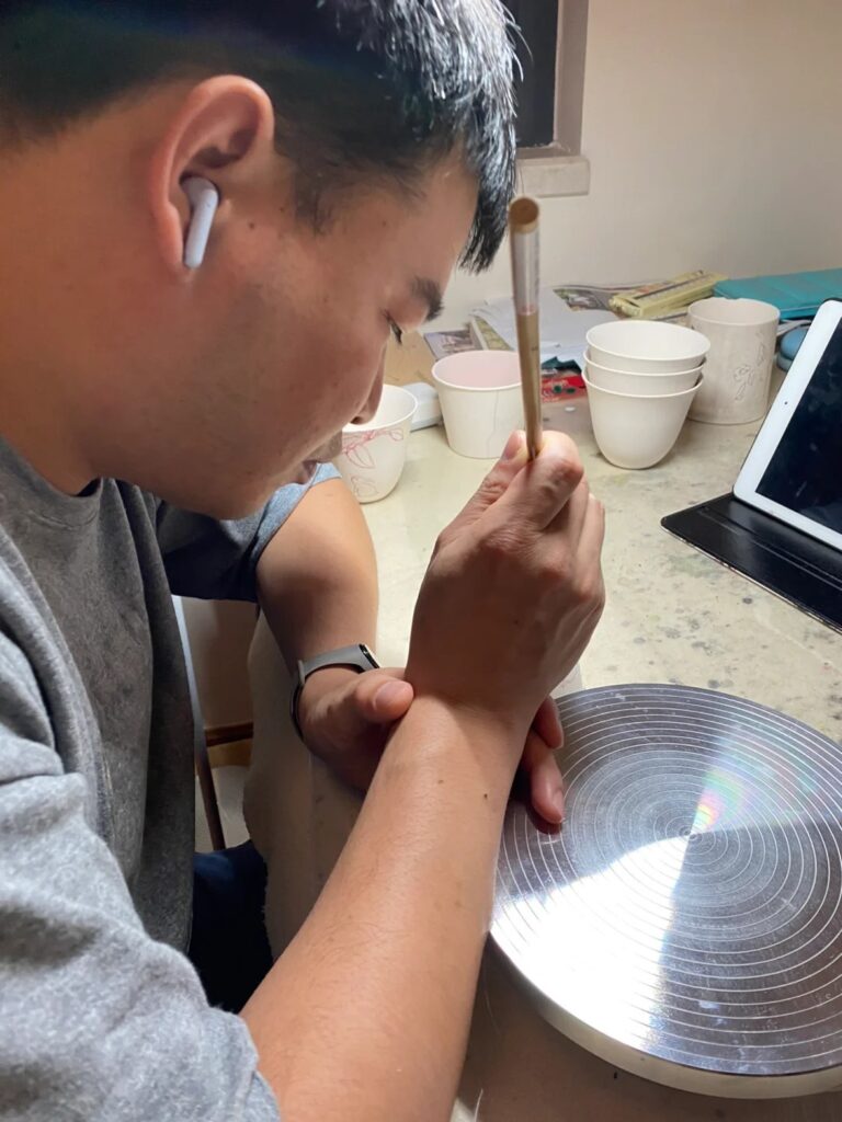 Peonyceramics artisan hand-painting a gourd design on a ceramic cup