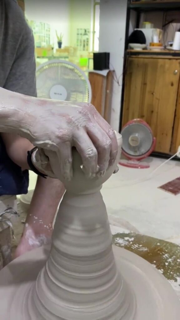 Handmade ceramics artist shaping a cup on the wheel using traditional hand-throwing technique