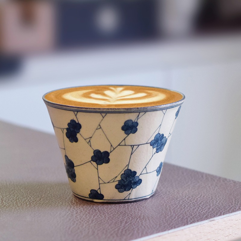 Artisan ceramic coffee cup featuring hand-painted winter plum blossoms
